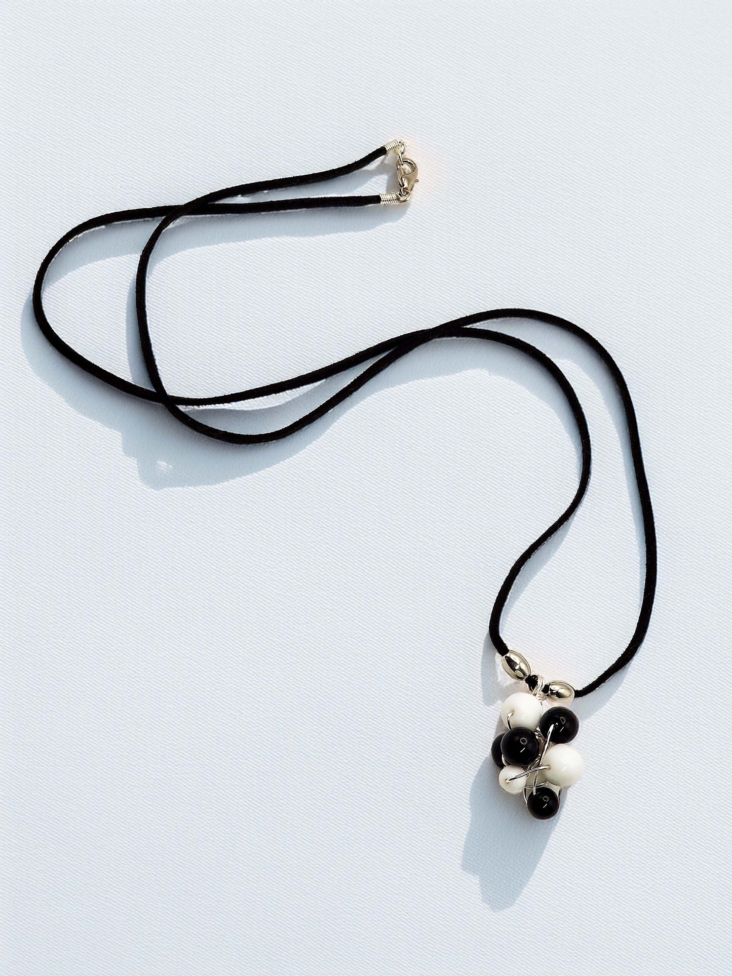 Necklace with a black cord and floral pendant on a light gray background