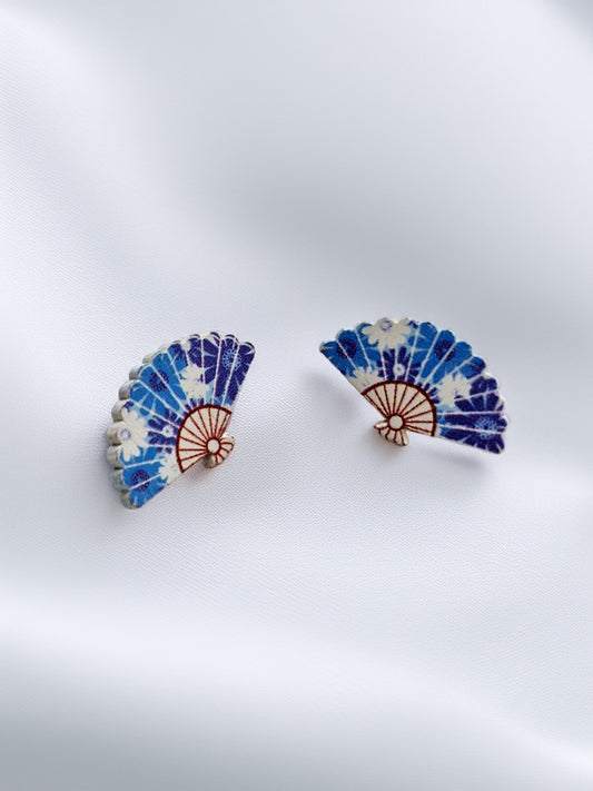 Pair of blue and white fan-shaped earrings on a light gray background