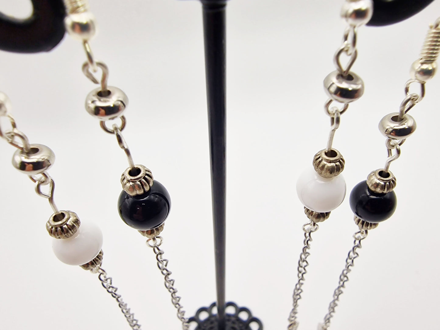 Close-up of beaded necklace with black and white beads on a stand.