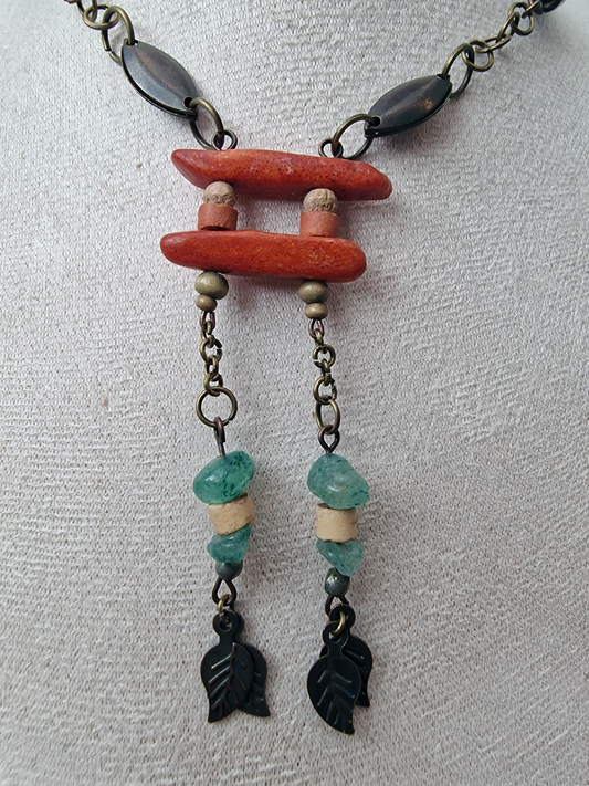 Necklace with red coral, turquoise, and black beads on a light gray background