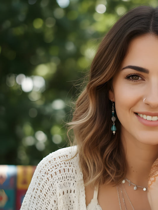 Woman with a smile, wearing earrings and a necklace, with a blurred green background