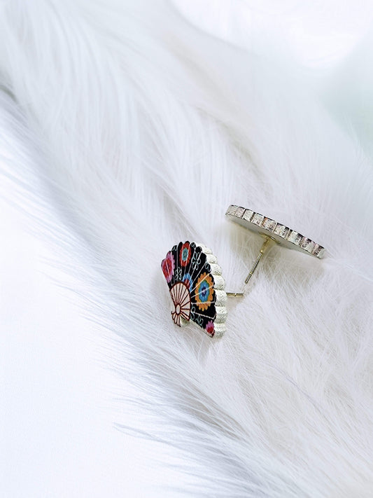 Colorful feather-shaped earring on a white fabric background