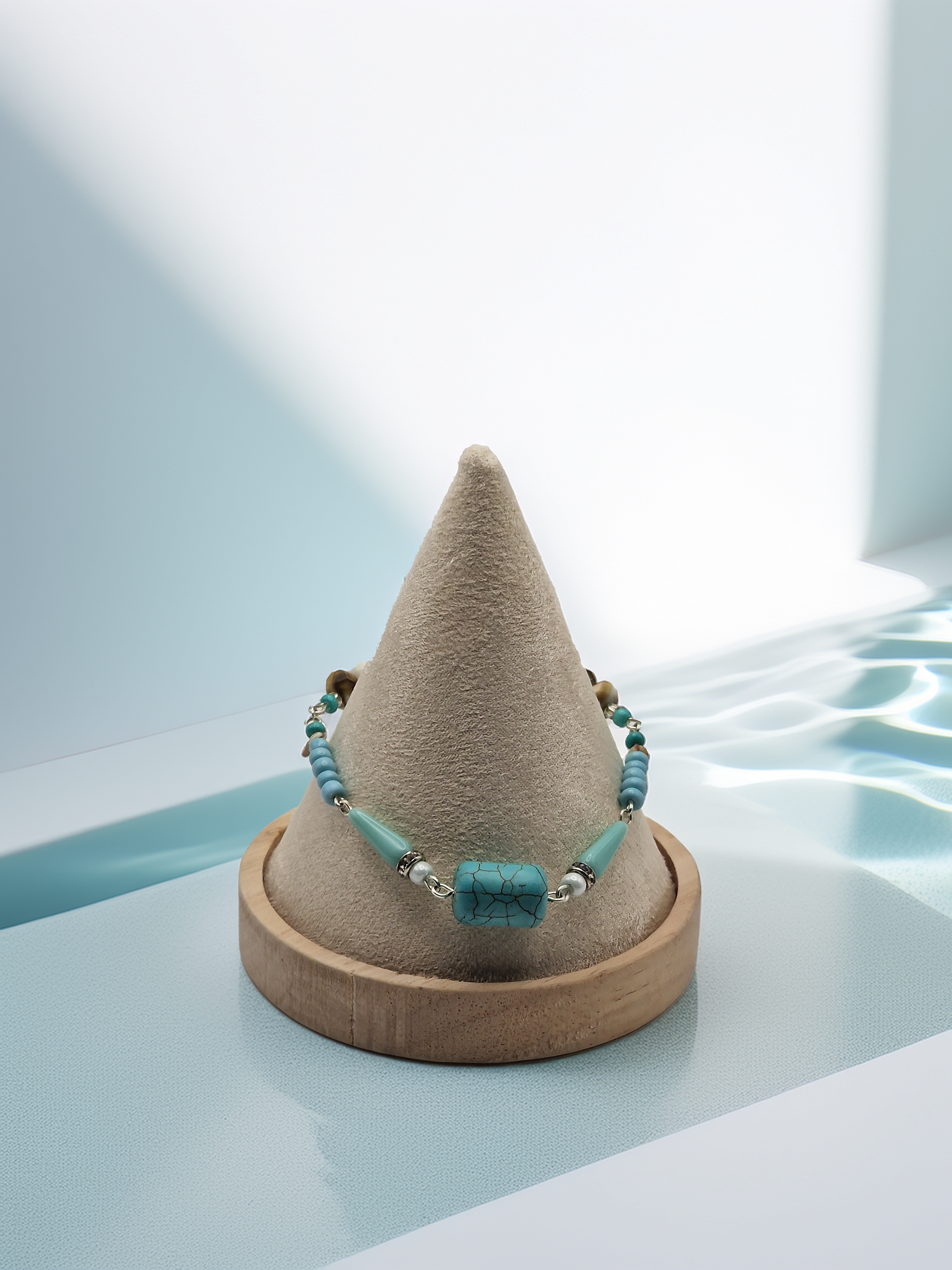 Turquoise beaded bracelet on a cone-shaped jewelry stand with a light blue background