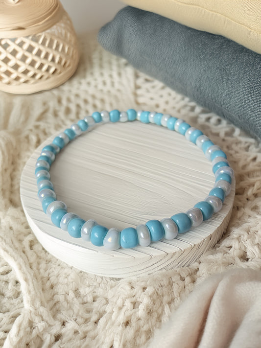 Blue beaded bracelet on a white dish with a textured surface