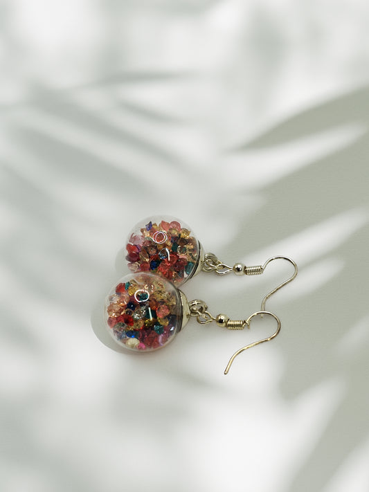 Clear glass bauble earrings with colourful beads on a white background