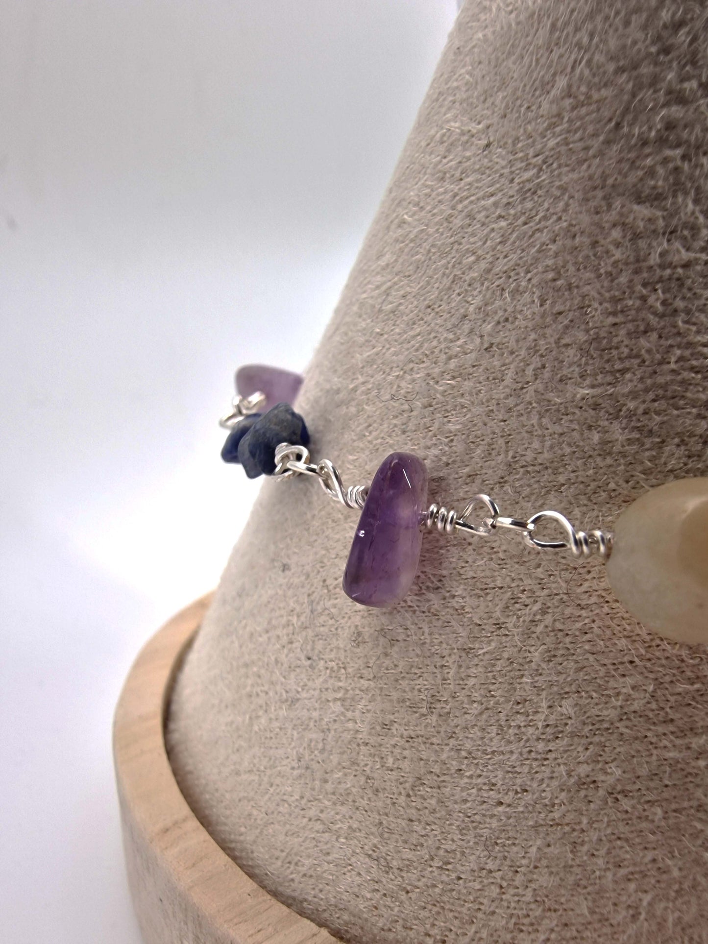 Amethyst bracelet on a wooden stand with a white background