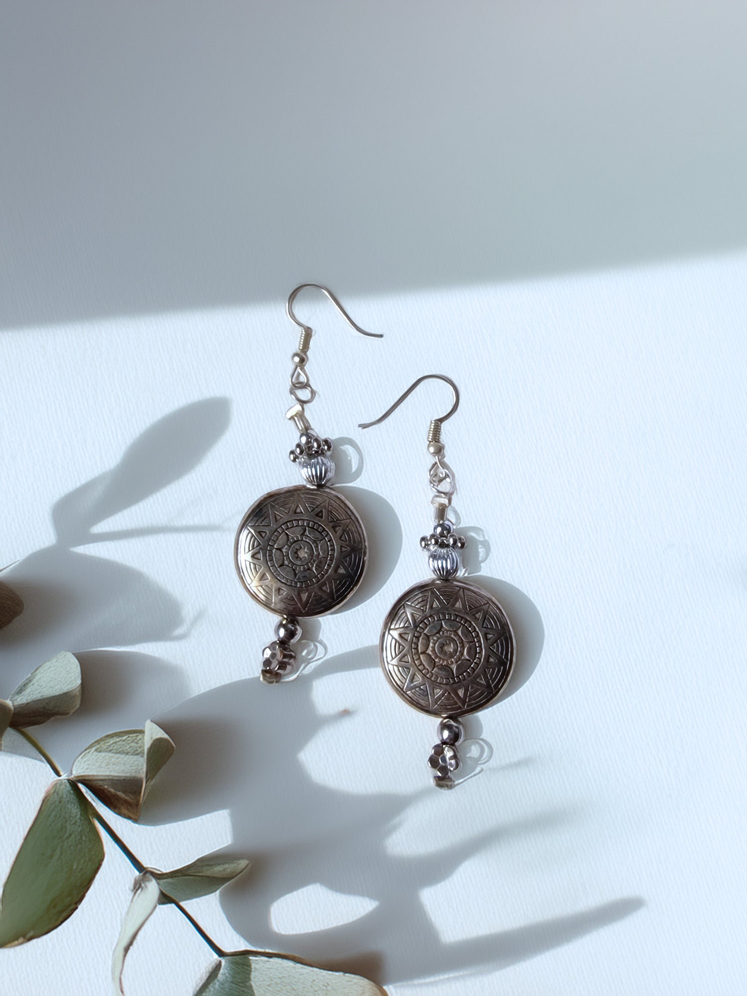 Pair of silver earrings with decorative elements on a light background