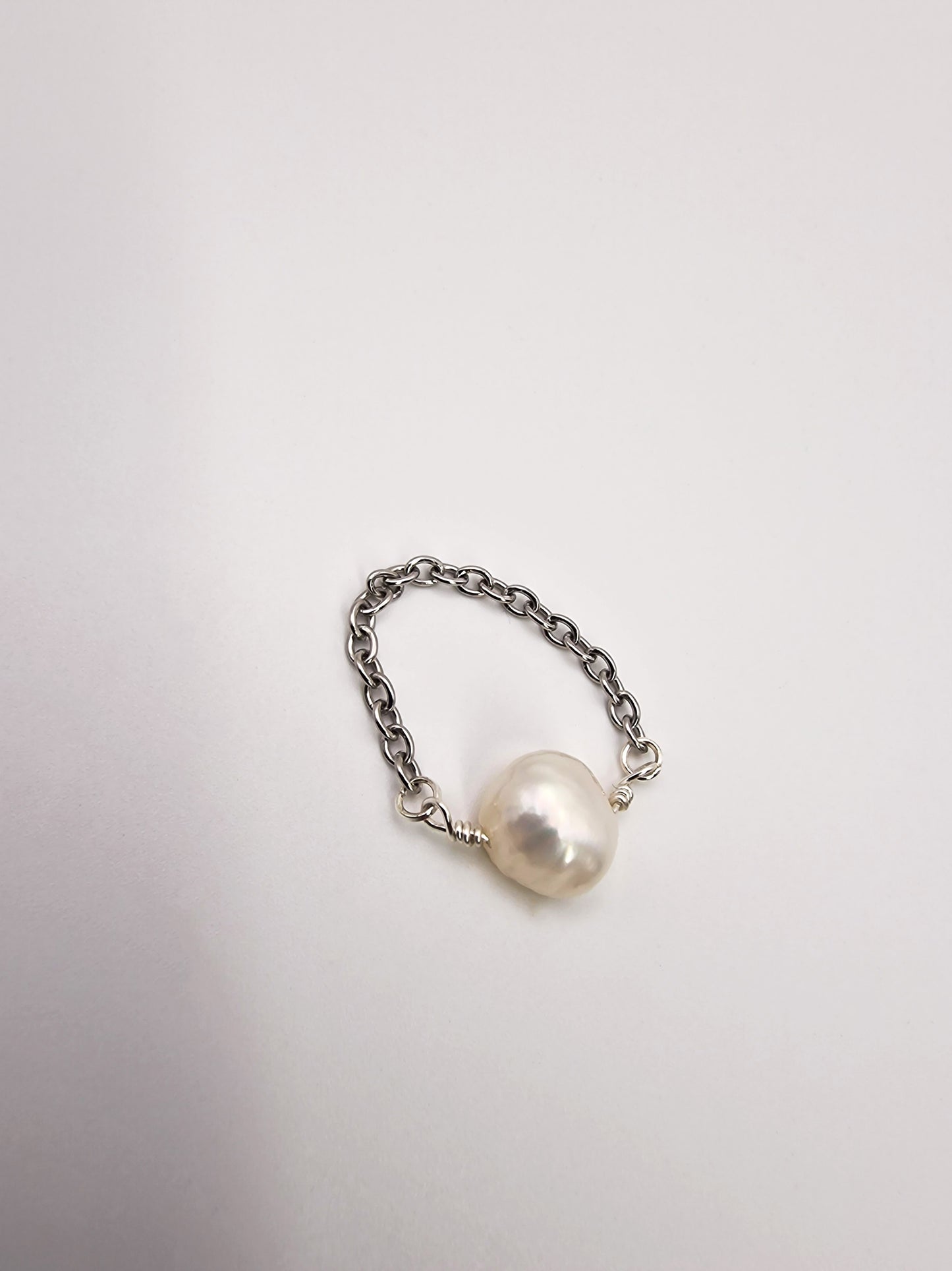 Silver chain ring with a pearl on a light gray background