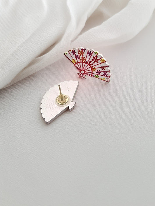 Two decorative earrings on a light fabric background