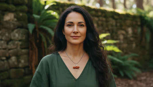Woman in a green shirt standing in front of a stone wall and plants
