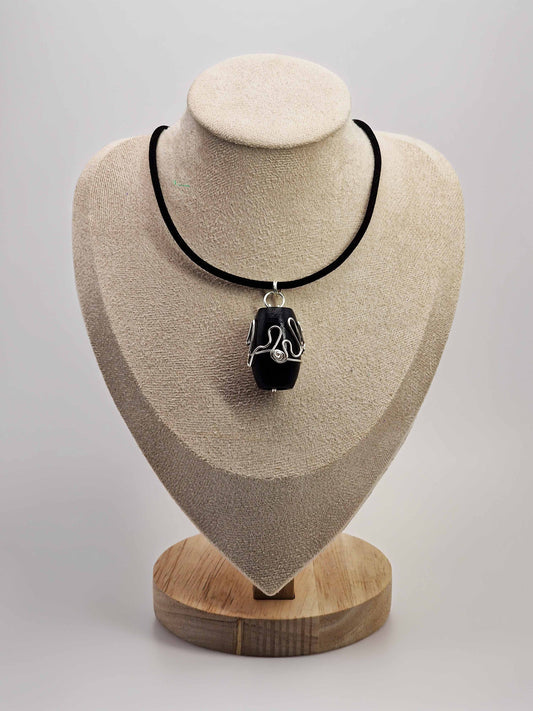 Necklace with a pendant on a beige display stand against a light gray background