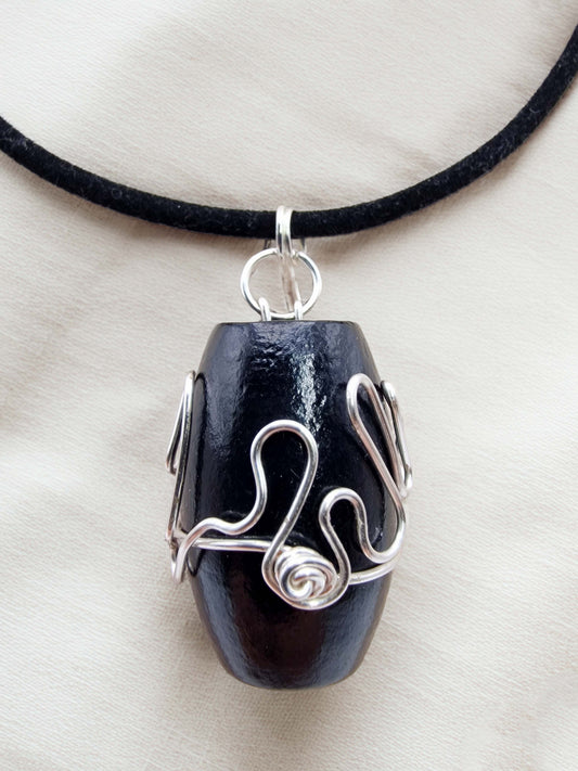 Black pendant with silver wire wrapping on a white background