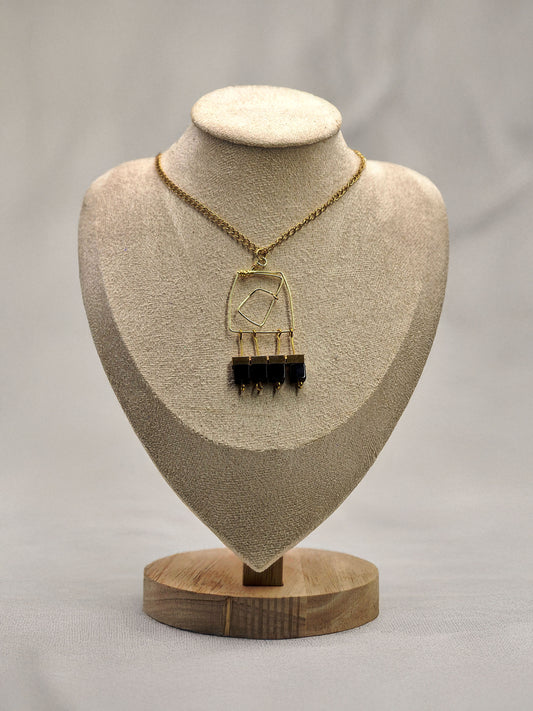 Necklace with a pendant on a beige bust against a gray background