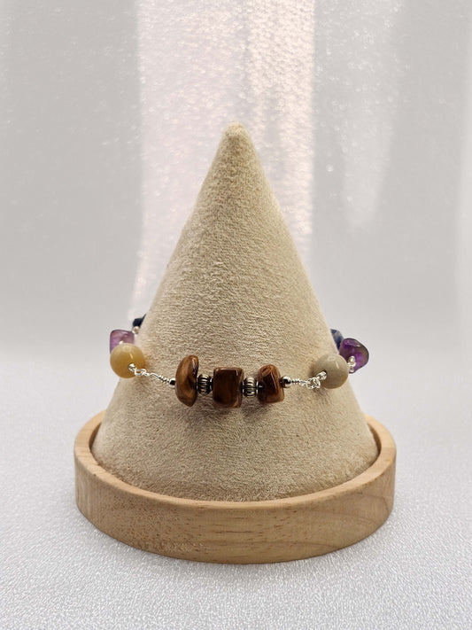 Bracelet with stones on a wooden stand against a neutral background