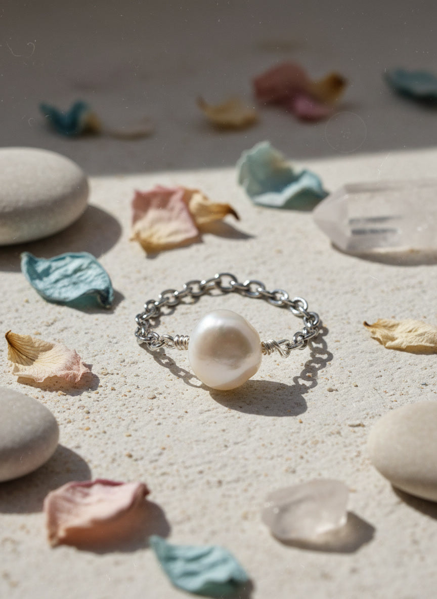 Pearl ring on a sandy surface with stones and dried leaves