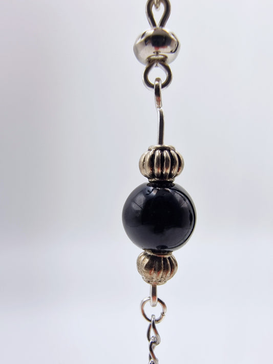 Close-up of a beaded chain with black glass and silver metal beads on a white background