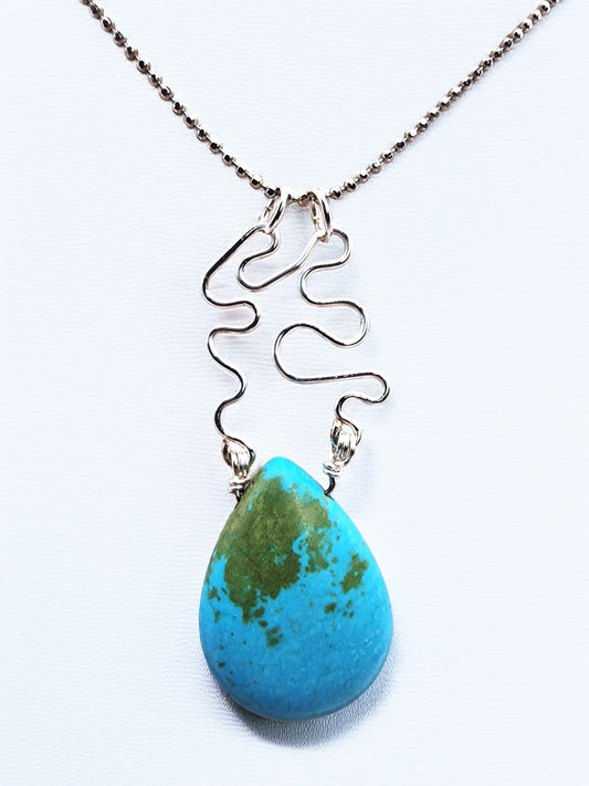 Turquoise teardrop pendant on a silver chain against a white background